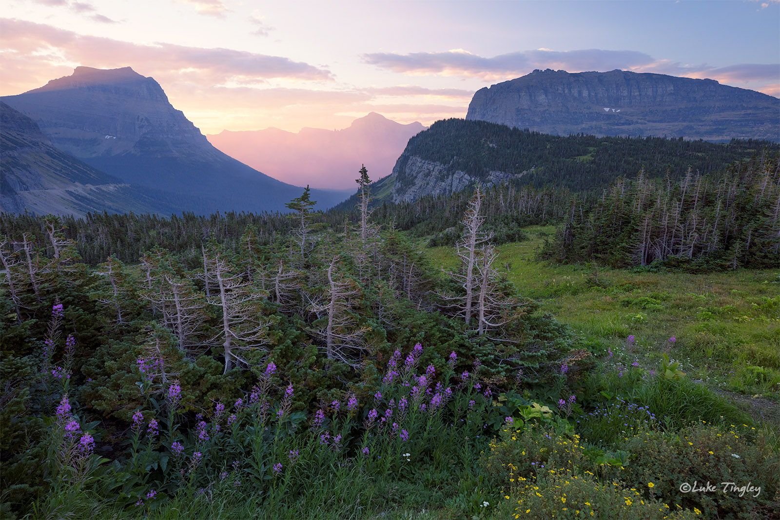 Smoke in the valley absorbs and radiates the early morning sunlight shooting through the valley in Glacier National Park.